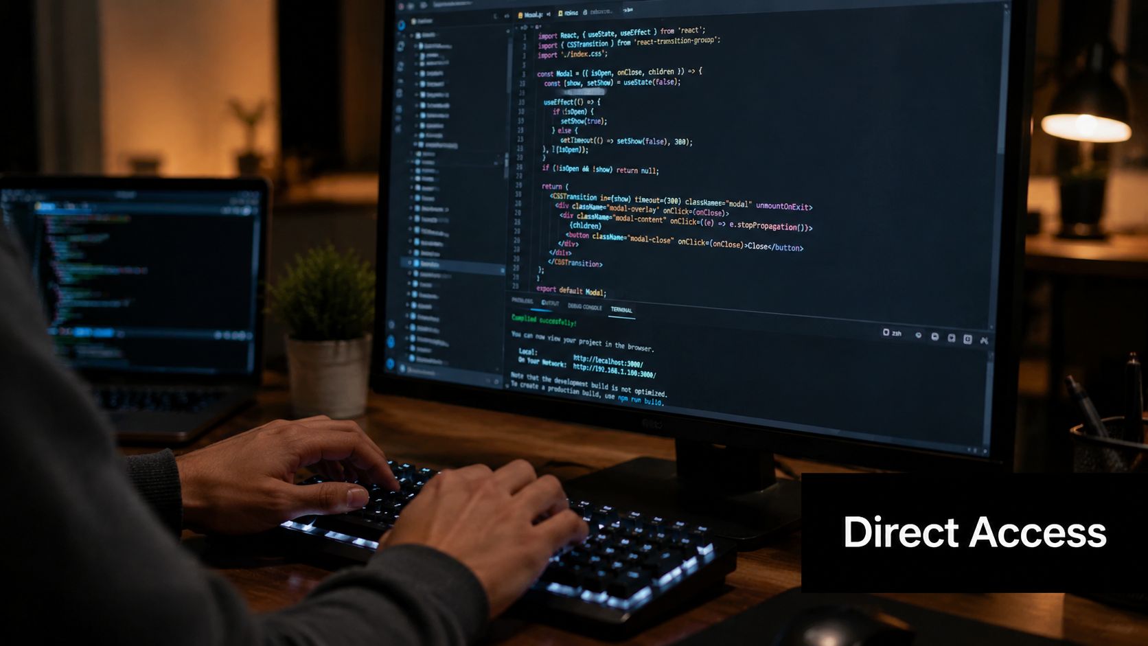 A developer coding on a desktop computer with code visible on the screen in a dimly lit office.